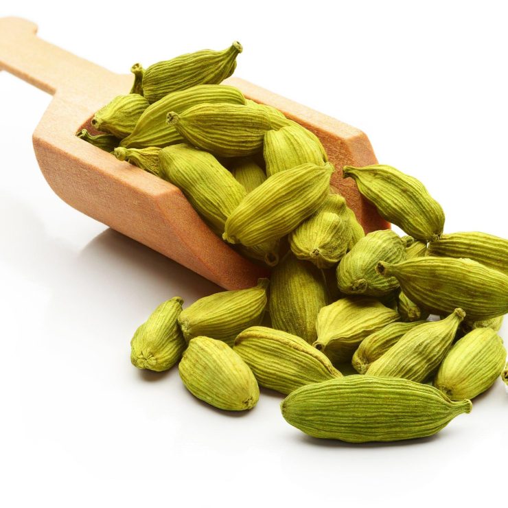 Cardamom seeds in a serving scoop. Isolated on a white background.