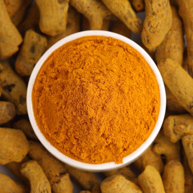 Dry Turmeric  with turmeric powder arranged in a white bowl  with white texture or background,top view