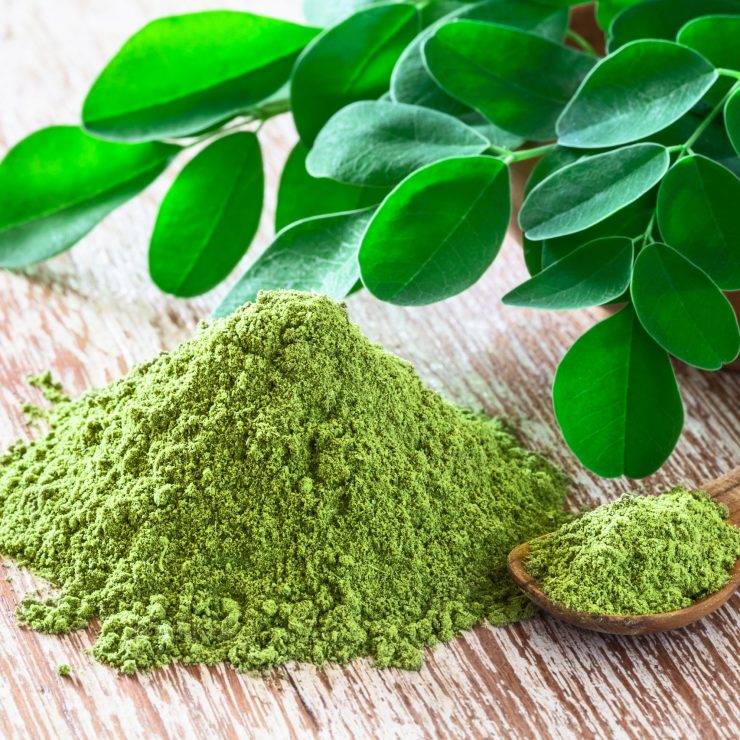 Moringa powder (Moringa Oleifera) with original fresh Moringa leaves on rustic background. Healthy product, superfood, vitamin.