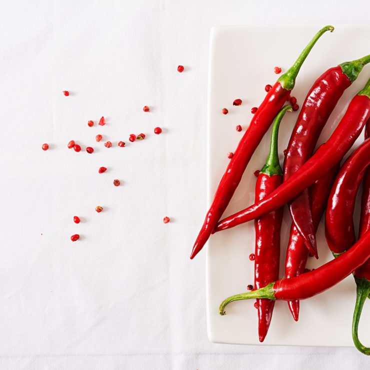 Red hot chili peppers in plate on white table. Top view. Flat lay